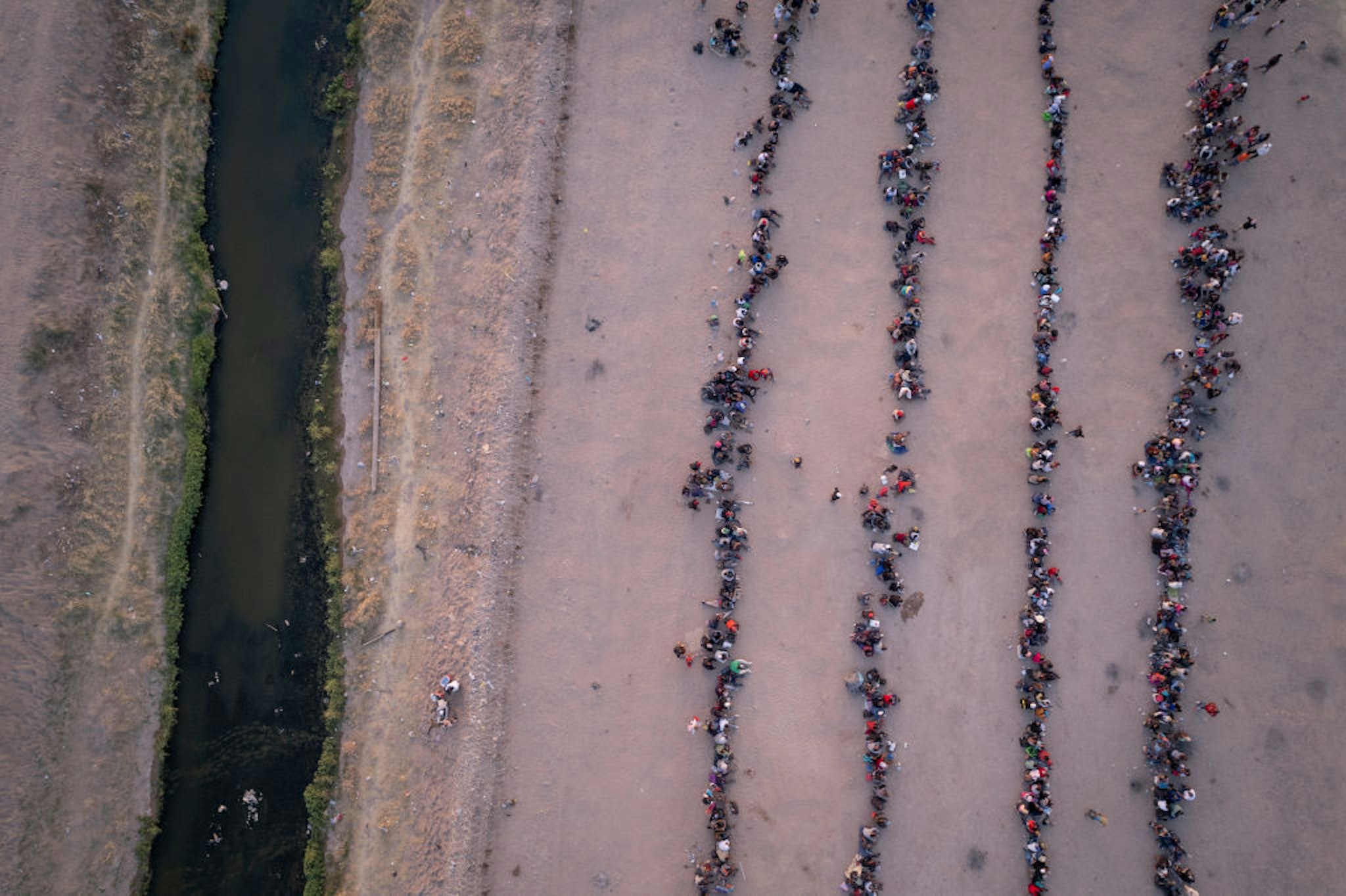 EL PASO, TEXAS - MAY 09: As seen from an aerial view, immigrants wait to be processed to make asylum claims after crossing the Rio Grande (L)from Mexico on May 09, 2023 in El Paso, Texas. A surge of immigrants is expected with the end of the U.S. government's Covid-era Title 42 policy, which for the past three years has allowed for the quick expulsion of irregular migrants entering the country.