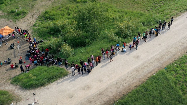 BROWNSVILLE, TEXAS - MAY 10: In this aerial view, migrants stand in line as they wait to be processed by the U.S. Border Patrol after crossing the border from Mexico on May 10, 2023 in Brownsville, Texas. A surge of immigrants is expected with the end of the U.S. government's Covid-era Title 42 policy, which for the past three years has allowed for the quick expulsion of irregular migrants entering the country. More than 29,000 individuals are in U.S. Customs and Border Protection custody, including nearly 18,000 in the last 24 hours. (Photo by Joe Raedle/Getty Images)