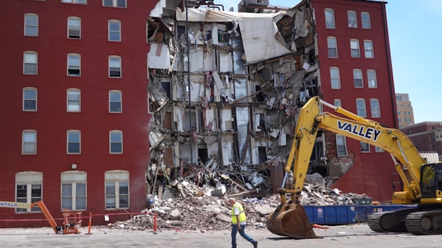DAVENPORT, IOWA - MAY 29: A worker walks by a six-story apartment building after it collapsed yesterday on May 29, 2023 in Davenport, Iowa. Eight people were rescued from the debris following the collapse yesterday afternoon.