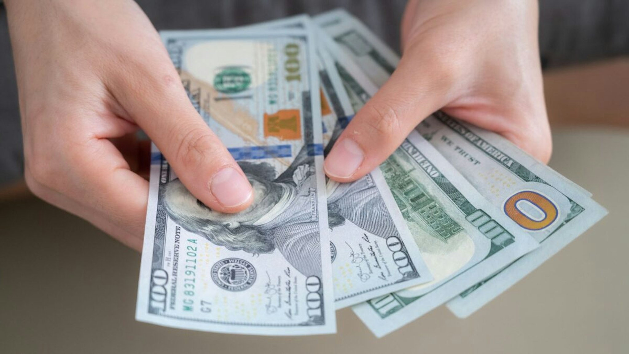 Close up of someone hands holding and counting American dollar banknotes in her hand. - stock photo