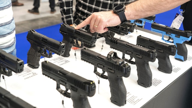 A vendor shows visitors different pistols at the SICUR 2022 International Security Show that opened today in Madrid (Spain)