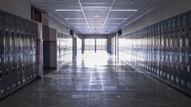 Empty high school corridor with lockers lining the walls - stock photo