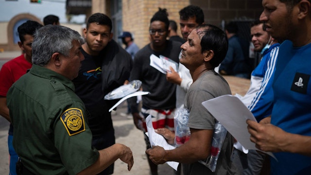 A Border Patrol agent speaks with migrants after they got off a bus at a processing center on May 11, 2023 in Brownsville, Texas. The US on May 11, 2023, will officially end its 40-month Covid-19 emergency, also discarding the Title 42 law, a tool that has been used to prevent millions of migrants from entering the country.