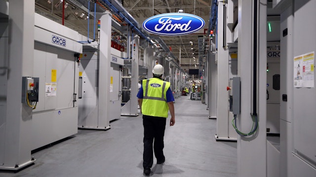 An employee walks past a Ford logo in the yet-to-be-completed engine production line at a Ford factory on January 13, 2015 in Dagenham, England.