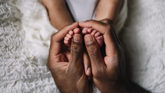 father hand with baby feet