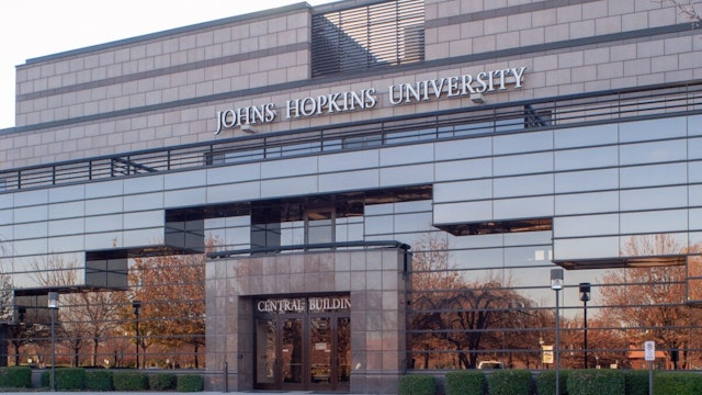 Slightly angled view of Gilchrist Hall, with autumnal trees reflected in the mirrored facade, at the Johns Hopkins University's Montgomery County Campus, Maryland, November 16, 2004. From the Homewood Photography Collection.