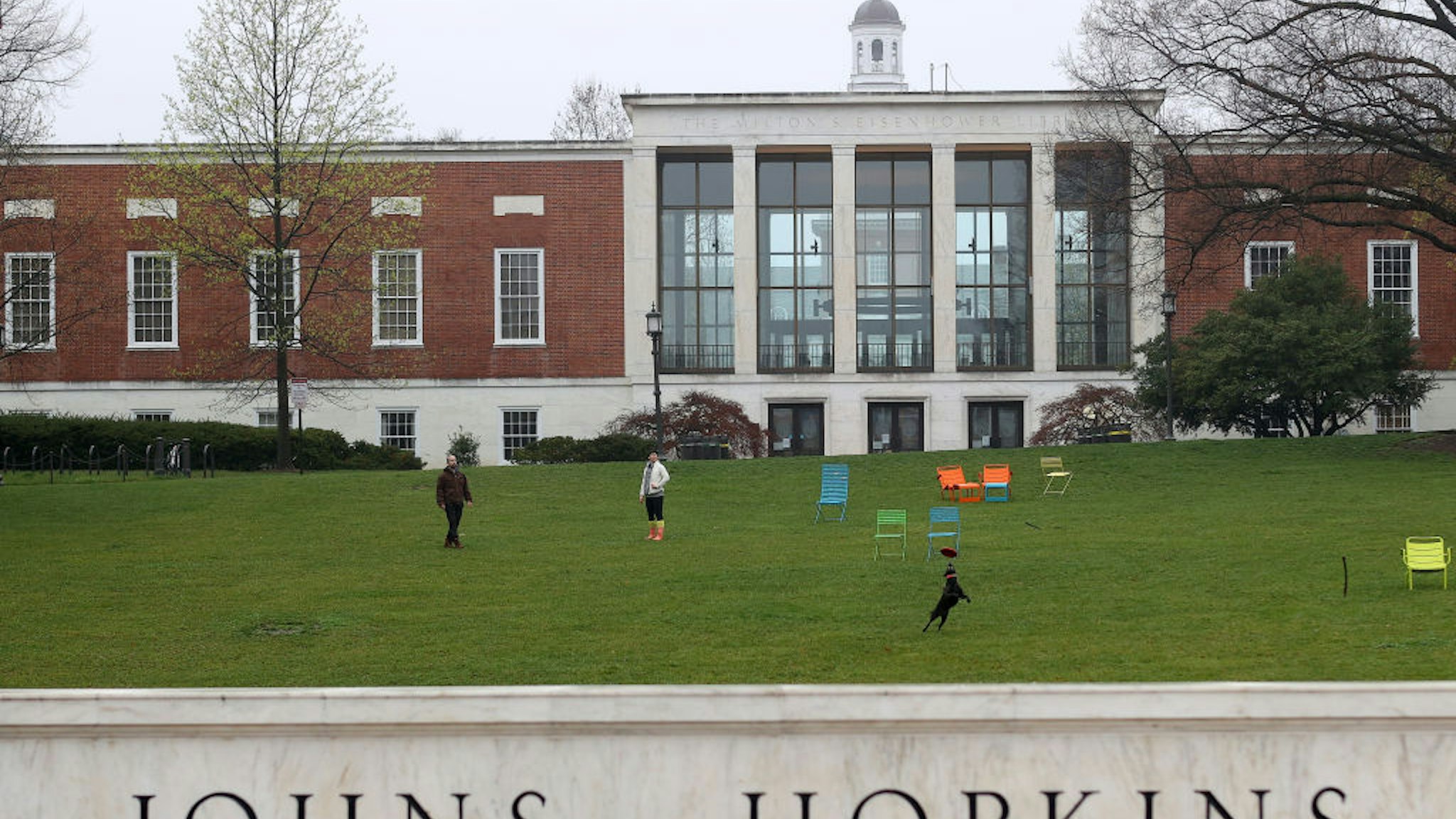 BALTIMORE, MARYLAND - MARCH 28: A couple throw a frisbee for a dog on the campus of The Johns Hopkins University on March 28, 2020 in Baltimore, Maryland. The school is shut down due to the coronavirus (COVID-19) outbreak. (Photo by Rob Carr/Getty Images)
