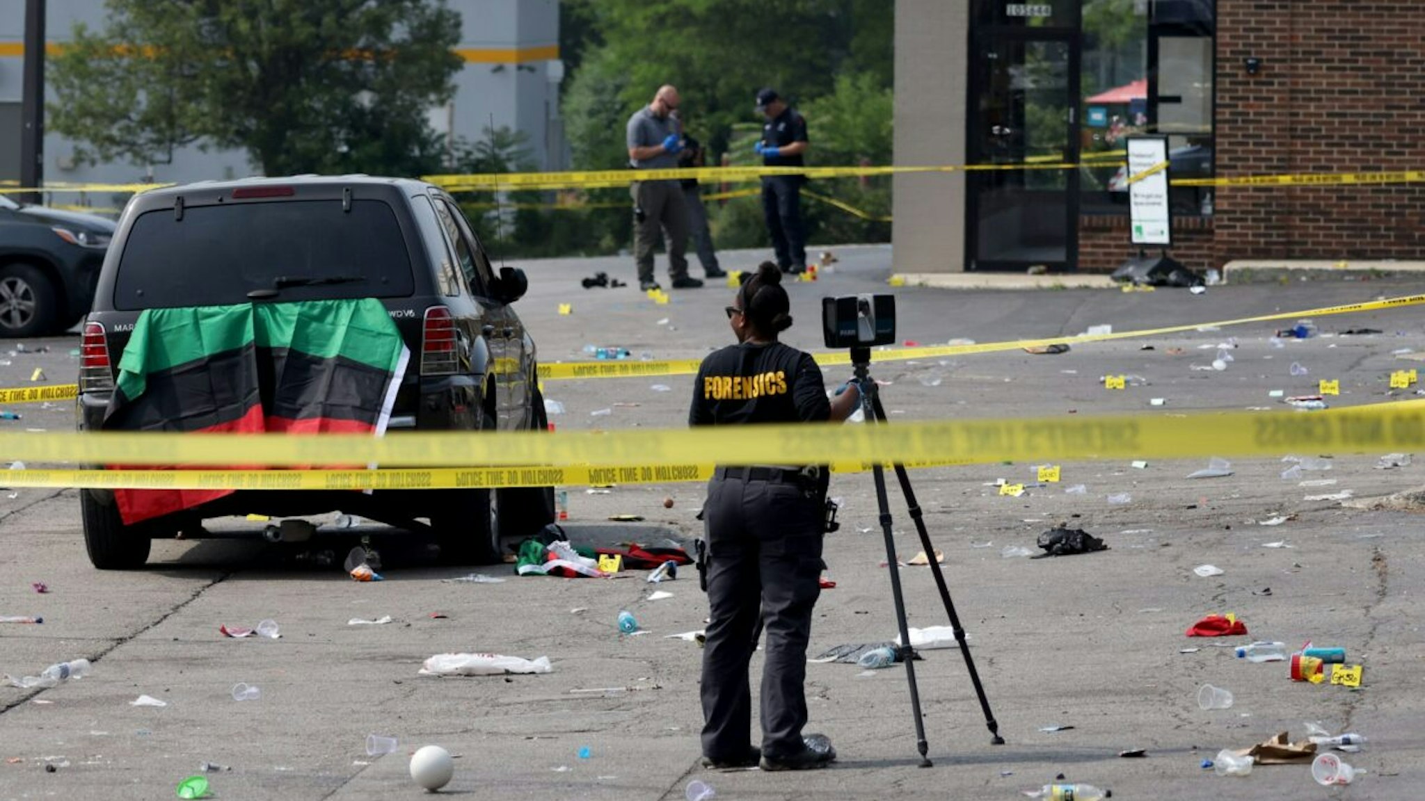 Police investigate the scene where approximately 16 people were shot, one fatally, in a parking lot outside BCD Liquors in Willowbrook, Illinois in the early hours of June 18, 2023.