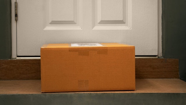 delivery cardboard box on doorsteps at home entrance door in evening