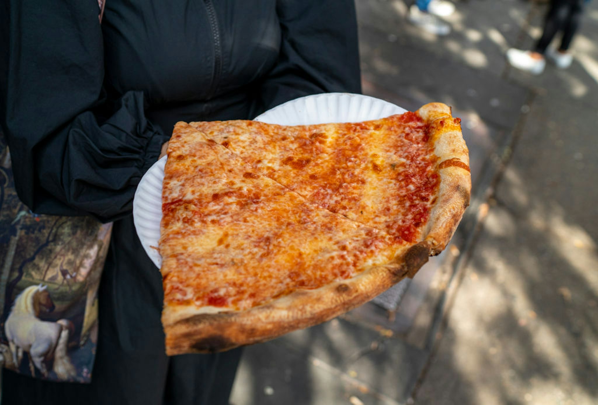 NEW YORK, NY - OCTOBER 23: A tourist carries freshly made pizza slices from Joe's Pizza on Carmine Street October 23, 2021 in New York City. Over 500,000 pizzas are sold everyday in New York City. (Photo by Robert Nickelsberg/Getty Images)