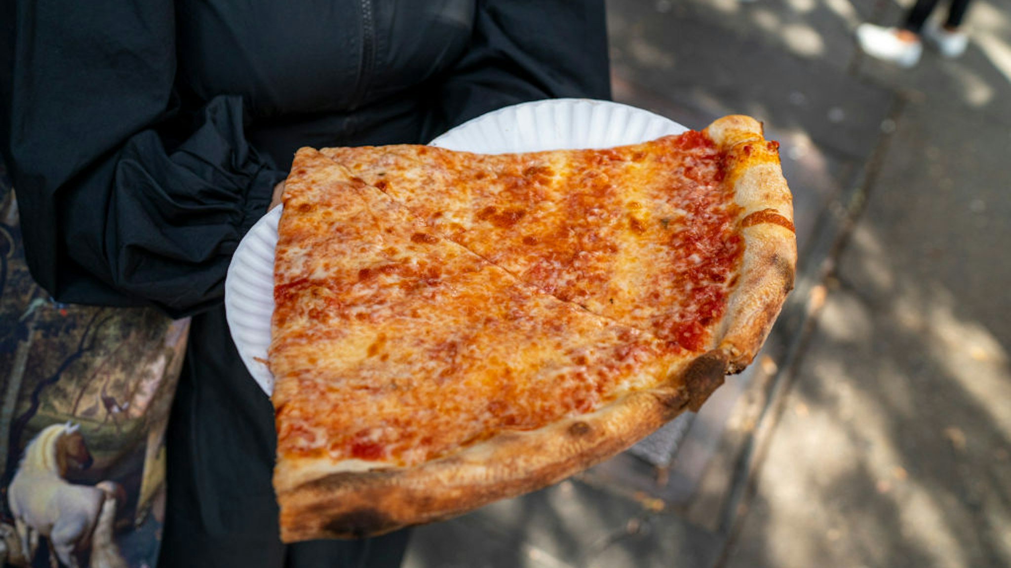 NEW YORK, NY - OCTOBER 23: A tourist carries freshly made pizza slices from Joe's Pizza on Carmine Street October 23, 2021 in New York City. Over 500,000 pizzas are sold everyday in New York City. (Photo by Robert Nickelsberg/Getty Images)
