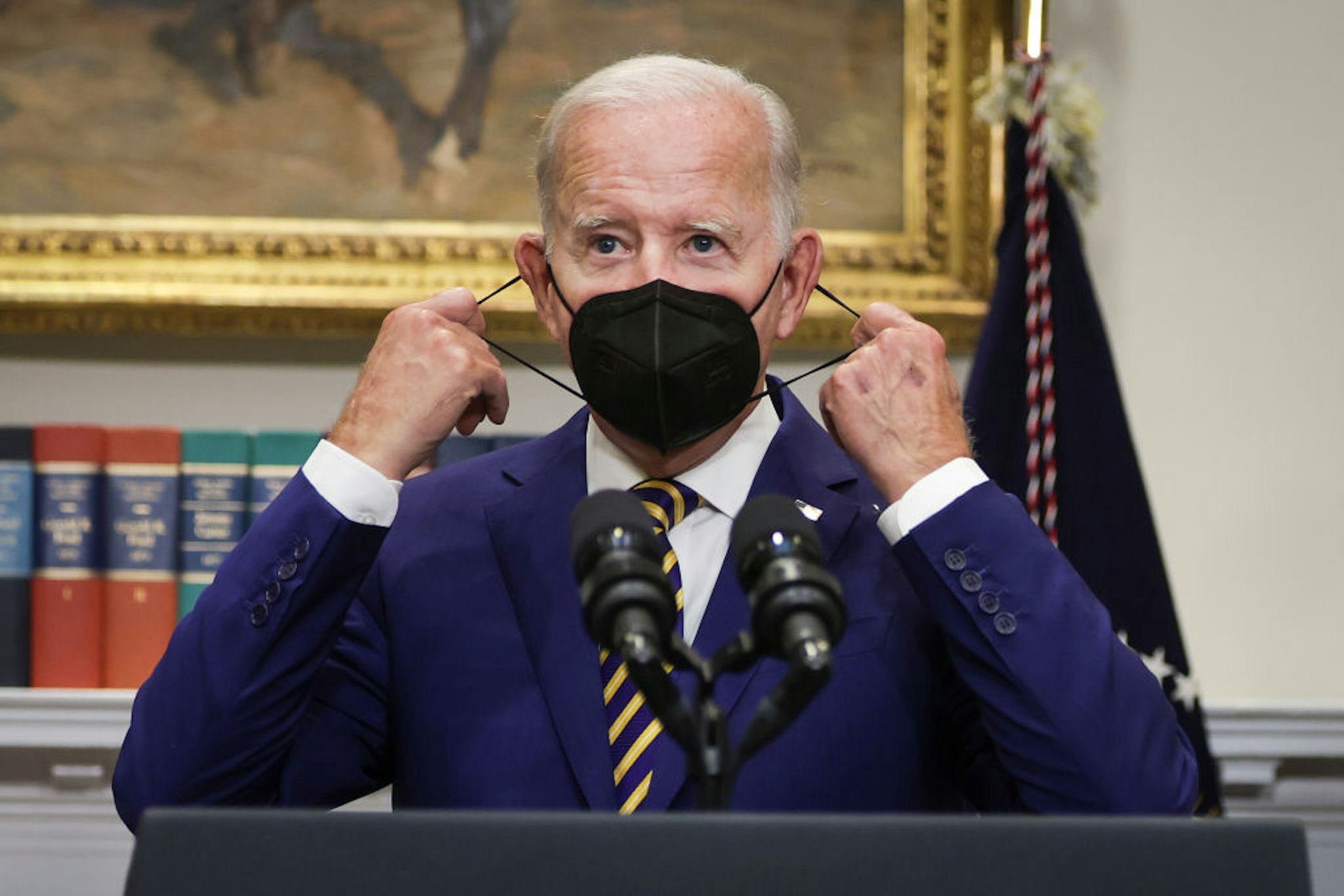 WASHINGTON, DC - AUGUST 24: U.S. President Joe Biden removes his mask before speaking on student loan debt in the Roosevelt Room of the White House August 24, 2022 in Washington, DC. President Biden announced steps to forgive $10,000 in student loan debt for borrowers who make less than $125,000 per year and cap payments at 5 percent of monthly income.