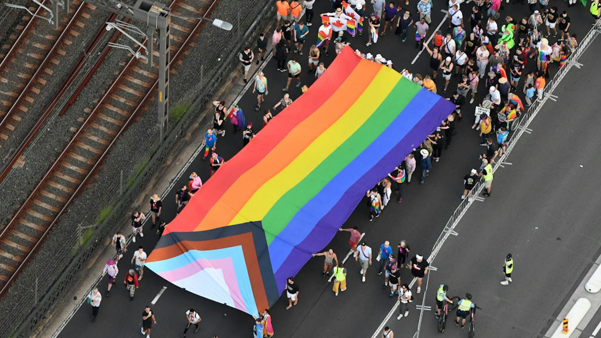 Sydney Makes History As 50,000 People March For Global Equality In Pride March SYDNEY, AUSTRALIA - MARCH 05: In this aerial view, the Progress Pride flag is carried over the Sydney Harbour Bridge as people take part in Pride March on March 05, 2023 in Sydney, Australia. 50,000 people marched across the iconic Sydney Harbour Bridge in their brightest colours to make a powerful international statement for global LGBTQIA+ equality. Pride March is one of more than 300 events in the Sydney WorldPride program, with the 17-day festival closing today. Pride March celebrates all that has been achieved, and acknowledges all that is still to be done, in the journey for global equality for the LGBTQIA+ community. Pride March also commemorates the 45th anniversary of Sydney Gay and Lesbian Mardi Gras, the 50th anniversary of the first Australian Gay Pride Week, and the 5th anniversary of marriage equality in Australia. Sydney also made history this year by becoming the first city in the Southern Hemisphere to host WorldPride.