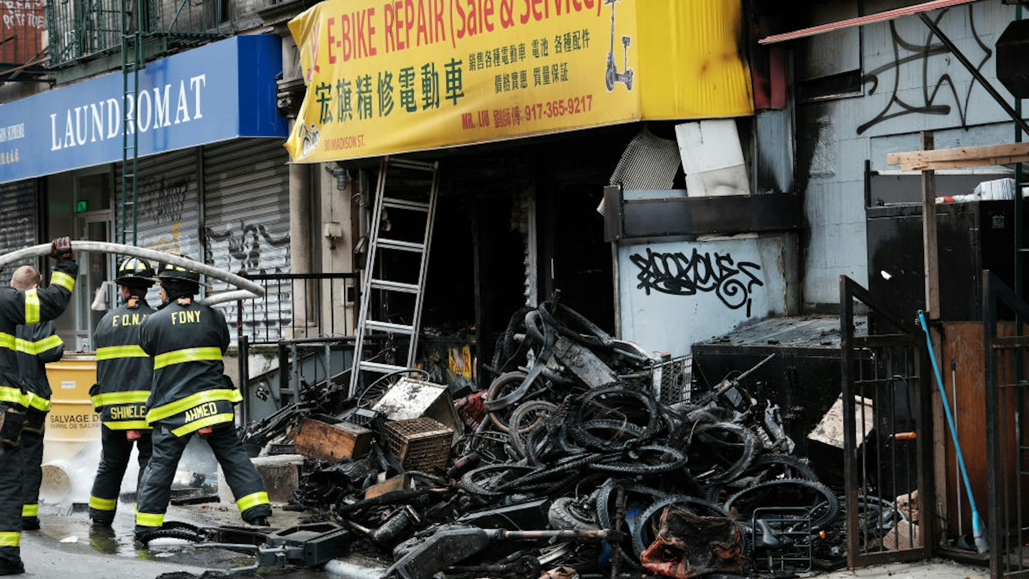 NEW YORK, NEW YORK - JUNE 20: Firefighters work outside a building in Chinatown after four people were killed by a fire in an e-bike repair shop overnight on June 20, 2023 in New York City. Lithium-ion e-bike batteries have caused numerous fires and fatalities in recent years due to the rising popularity of e-bikes for delivery purposes. New York City Mayor Eric Adams' administration has taken strong measures against unregulated e-bike and e-scooter batteries, which often present the highest risk when improperly charged.
