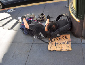 SAN FRANCISCO, CA - OCTOBER 4, 2013: A homeless man sleeps on a sidewalk in San Francisco's Union Square district. His sign declares that he is 'broke and hungry' and 'needs weed.' (Photo by Robert Alexander/Getty Images)