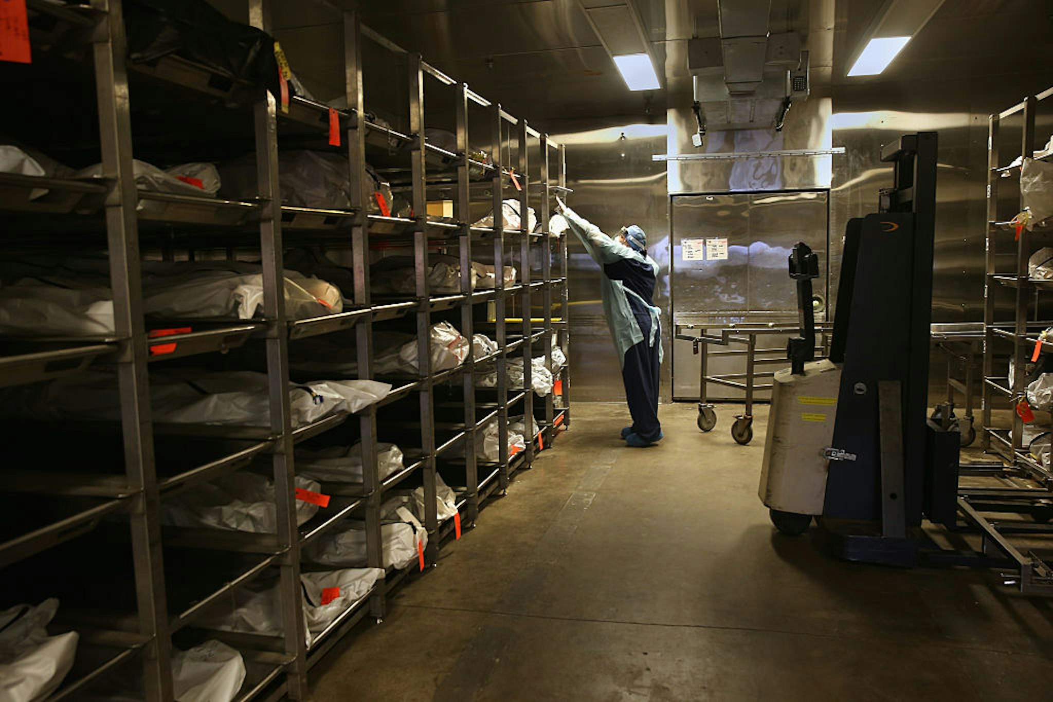 TUCSON, AZ - DECEMBER 09: Forensic technician Kristine Clor handles human remains in the refrigerated morgue of the Pima County Office of the Medical Examiner on December 9, 2014 in Tucson, Arizona. Forensic anthropologists attempt to identify the deceased by studying personal effects and bodily remains. Most are from undocumented immigrants, many of whom died of dehydration while crossing illegally into the U.S. from Mexico. The center currently has 90 bodies in the morgue and, on average, receives 176 per year, most found by ranchers and Border Patrol agents. Identified remains are repatriated, along with personal items, to their home countries, and the others will be cremated. (Photo by John Moore/Getty Images)