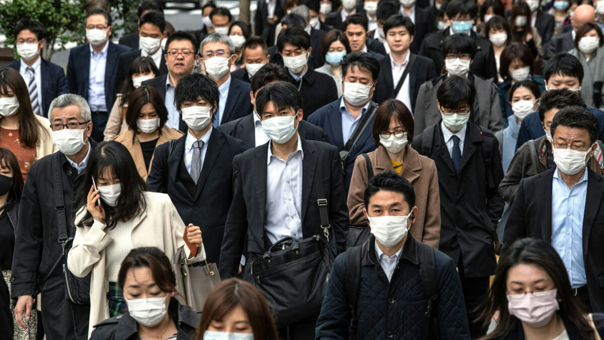 TOKYO, JAPAN - APRIL 07: Commuters wearing face masks walk to work the day before a state of emergency is expected to be imposed on April 7, 2020 in Tokyo, Japan. Japans Prime Minister, Shinzo Abe, yesterday announced that the government intends to declare a state of emergency that will cover 7 of Japans 47 prefectures, including Tokyo and Osaka, as the Covid-19 coronavirus outbreak continues to spread in the country. The move will allow affected prefectures to take measures including expropriating private land and buildings and requisitioning medical supplies and food from companies that refuse to sell them.