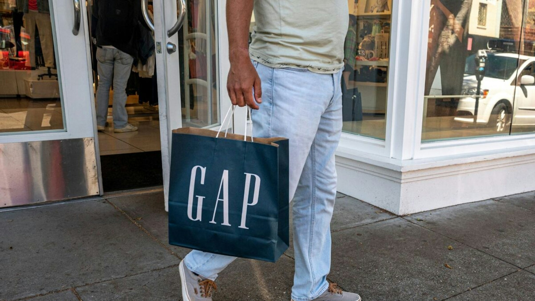A shopper carries a Gap bag outside a store in San Francisco, California, US, on Thursday, April 27, 2023.