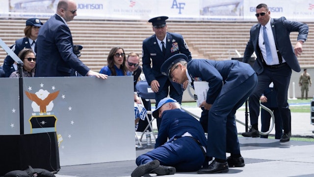 US President Joe Biden is helped up after falling during the graduation ceremony at the United States Air Force Academy, just north of Colorado Springs in El Paso County, Colorado, on June 1, 2023. (