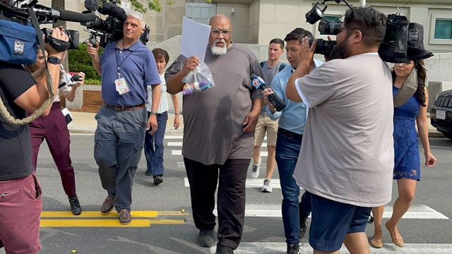 Concord, NH - June 14: Former Harvard Medical School morgue manager Cedric Lodge, 55, shields his face with a printout of the indictment against him as he walked from the Warren B. Rudman United States Courthouse, following his arrest on charges related to an alleged scheme to steal and sell donated body parts.
