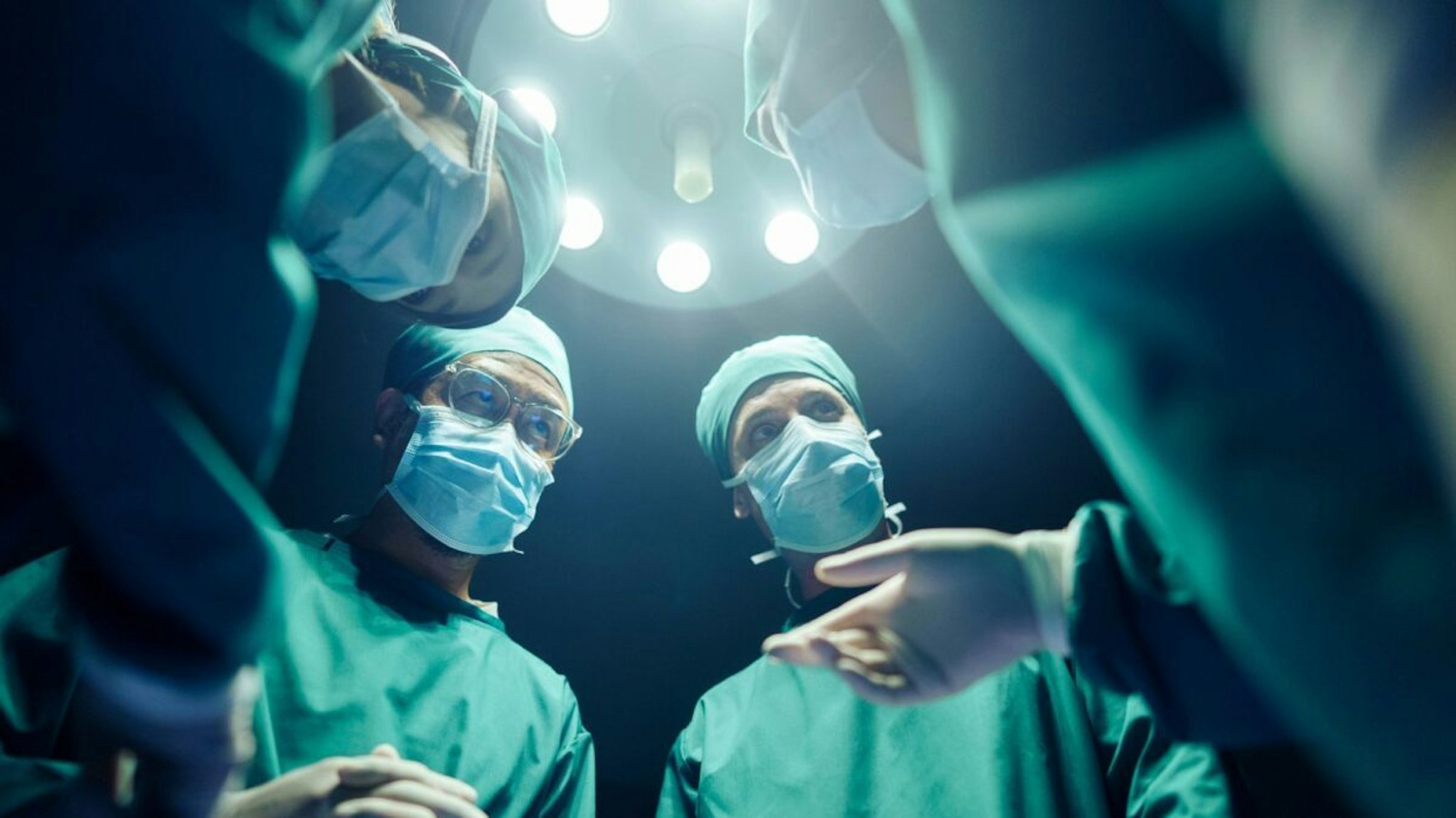 Low angle Four Surgeons coordinating their operating cases While in the operating room, teamwork and Cooperation - stock photo