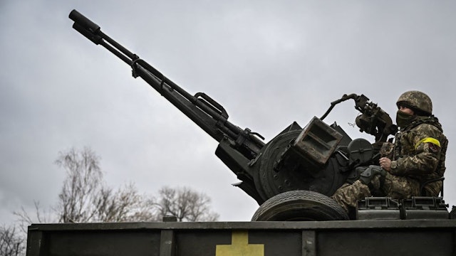 An Ukrainian soldier keeps position sitting on a ZU-23-2 anti-aircraft gun at a frontline, northeast of Kyiv on March 3, 2022. - A Ukrainian negotiator headed for ceasefire talks with Russia said on March 3, 2022, that his objective was securing humanitarian corridors, as Russian troops advance one week into their invasion of the Ukraine. (Photo by Aris Messinis / AFP)