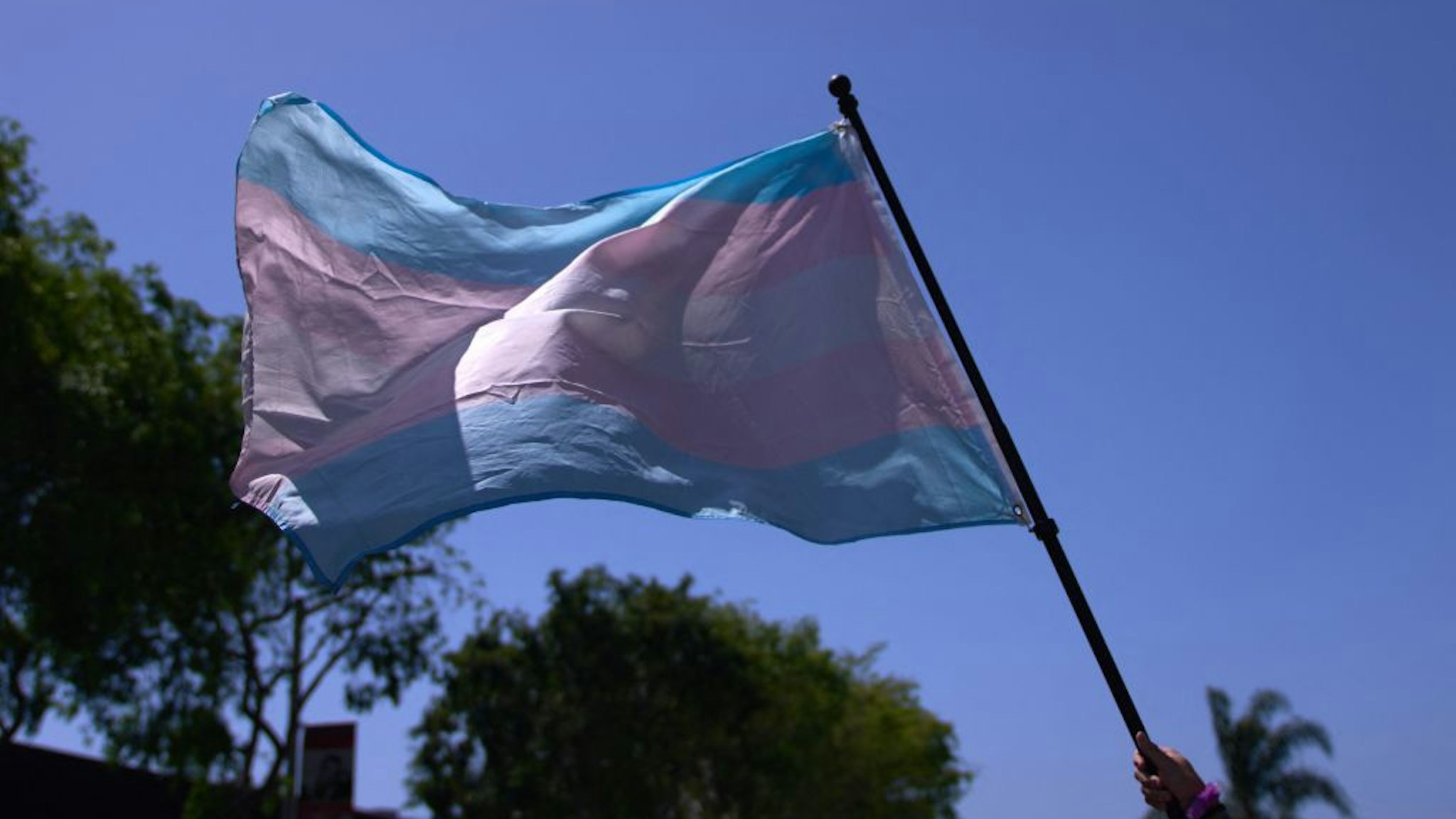 A Transgender Pride Flag is held above the crowd of LGBTQ+ activists during the Los Angeles LGBT Center's "Drag March LA: The March on Santa Monica Boulevard", in West Hollywood, California, on Easter Sunday April 9, 2023. - The march comes in response to more than 400 pieces of legislation targeting the LGBTQ+ community that government officials across the United States have proposed or passed in 2023. (Photo by ALLISON DINNER / AFP) (Photo by ALLISON DINNER/AFP via Getty Images)