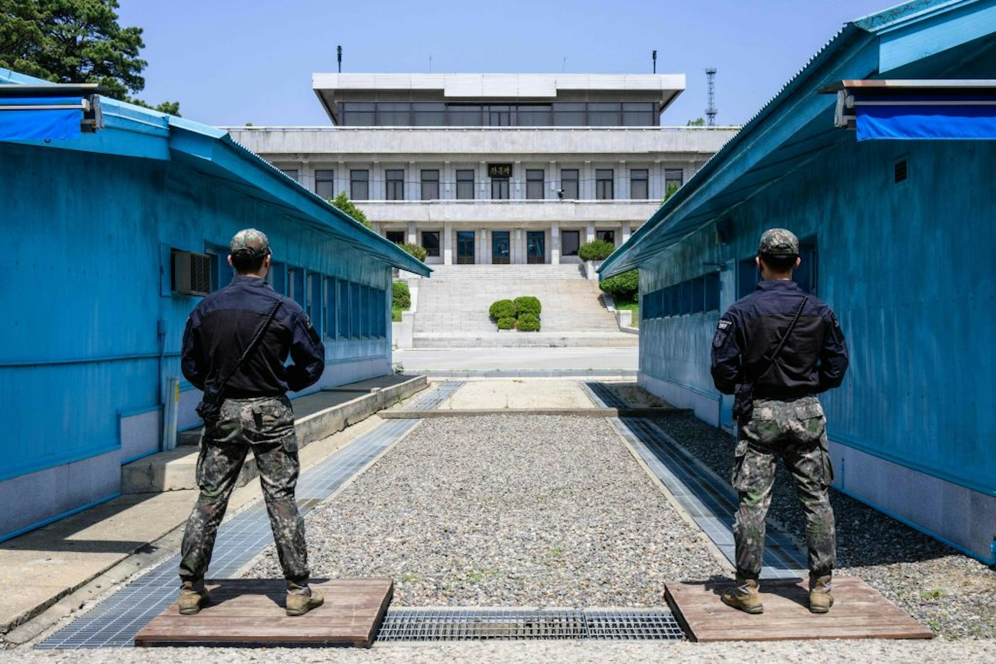  Two soldiers stand guard at the DMZ between North and South Korea, a line of blue propaganda balloons in the foreground.