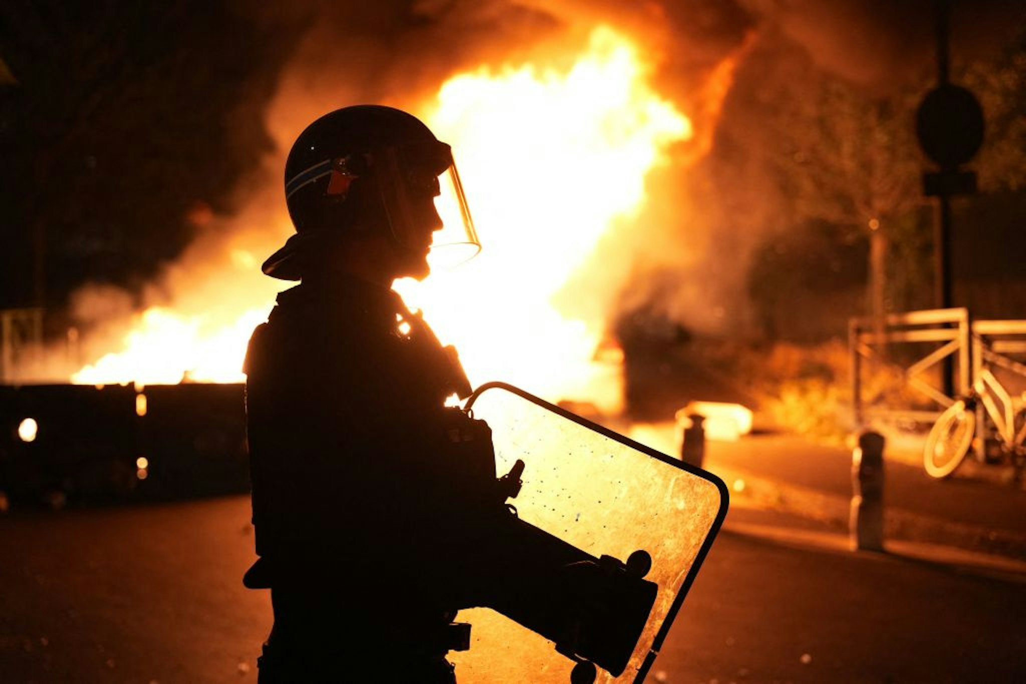 TOPSHOT - A firefighter looks on as vehicles burn following riots in Nanterre, west of Paris, on June 28, 2023, a day after a 17-year-old boy was shot in the chest by police at point-blank range in this western suburb of Paris. Violent protests broke out in France in the early hours of June 29, 2023, as anger grows over the police killing of a teenager, with security forces arresting 150 people in the chaos that saw balaclava-clad protesters burning cars and setting off fireworks. Nahel M., 17, was shot in the chest at point-blank range on June 27, 2023, morning in an incident that has reignited debate in France about police tactics long criticised by rights groups over the treatment of people in low-income suburbs, particularly ethnic minorities. (Photo by Zakaria ABDELKAFI / AFP)