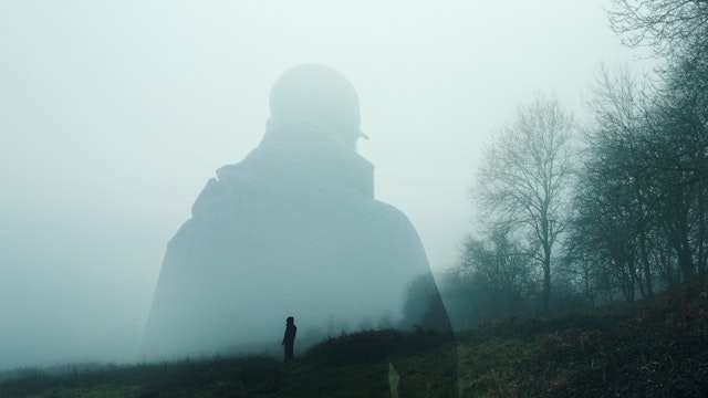 double exposure of an atmospheric half transparent man looking at a person standing on the edge of a forest in the countryside. On a moody foggy winters day. - stock photo