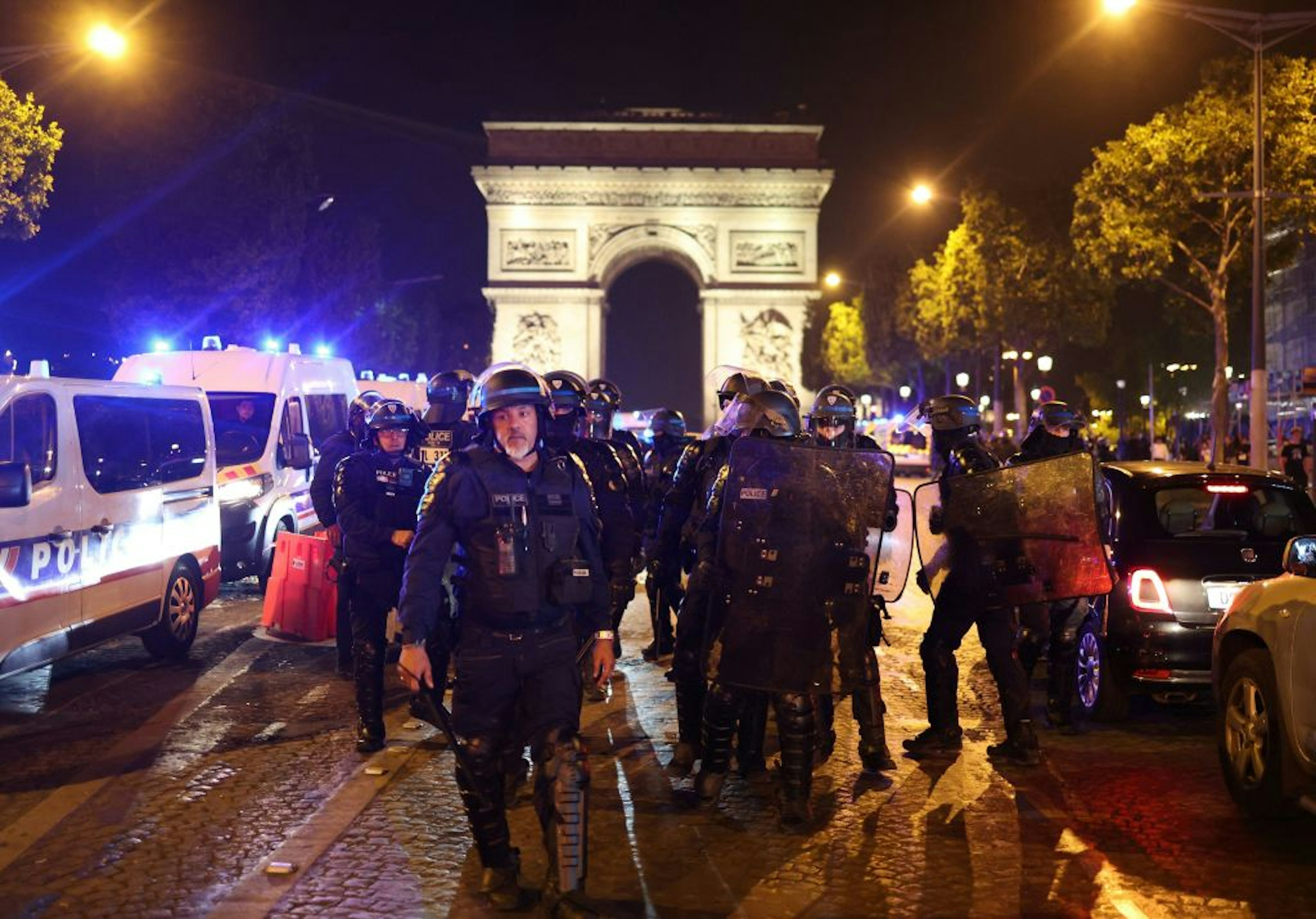 TOPSHOT - French police officers patrol in front of the Arc de Triomphe in the Champs Elysees area of Paris on July 1, 2023, five days after a 17-year-old man was killed by police in Nanterre, a western suburb of Paris. French police arrested 1311 people nationwide during a fourth consecutive night of rioting over the killing of a teenager by police, the interior ministry said on July 1, 2023. France had deployed 45,000 officers overnight backed by light armoured vehicles and crack police units to quell the violence over the death of 17-year-old Nahel, killed during a traffic stop in a Paris suburb on June 27, 2023. (Photo by CHARLY TRIBALLEAU / AFP) (Photo by CHARLY TRIBALLEAU/AFP via Getty Images)