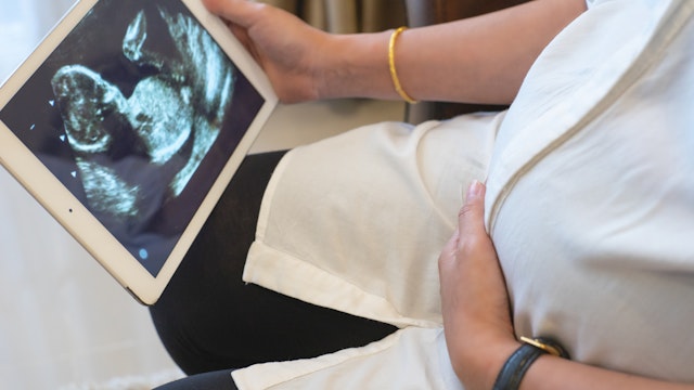 Pregnant Woman Showing Ultrasound Image On Digital Tablet