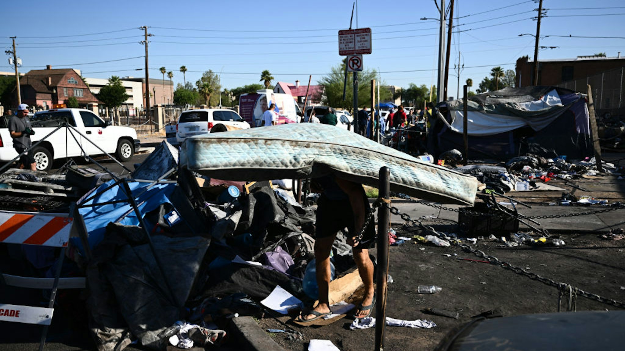 TOPSHOT - A person carries a mattress from a tent during a sweep of encampments from a street block in "The Zone," a vast homeless encampment where hundreds of people reside, during a record heat wave in Phoenix, Arizona on July 19, 2023. Phoenix, like much of the US southwest, is surrounded by desert and its 1.6 million residents are used to brutal summer temperatures. But this year's heat wave is unprecedented in its length: it has already surpassed the previous record of 18 straight days at or above 110 degrees Fahrenheit (43 degrees Celsius), with similar highs forecasted into next week. And as global warming fuels more frequent extreme weather events, homeless people are increasingly vulnerable to the elements. (Photo by Patrick T. Fallon / AFP) (Photo by PATRICK T. FALLON/AFP via Getty Images)