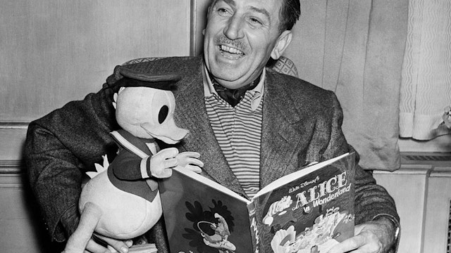 Film producer and cartoonist Walt Disney with a toy Donald Duck reading Alice in Wonderland, 1951. (Photo by © Hulton-Deutsch Collection/CORBIS/Corbis via Getty Images)