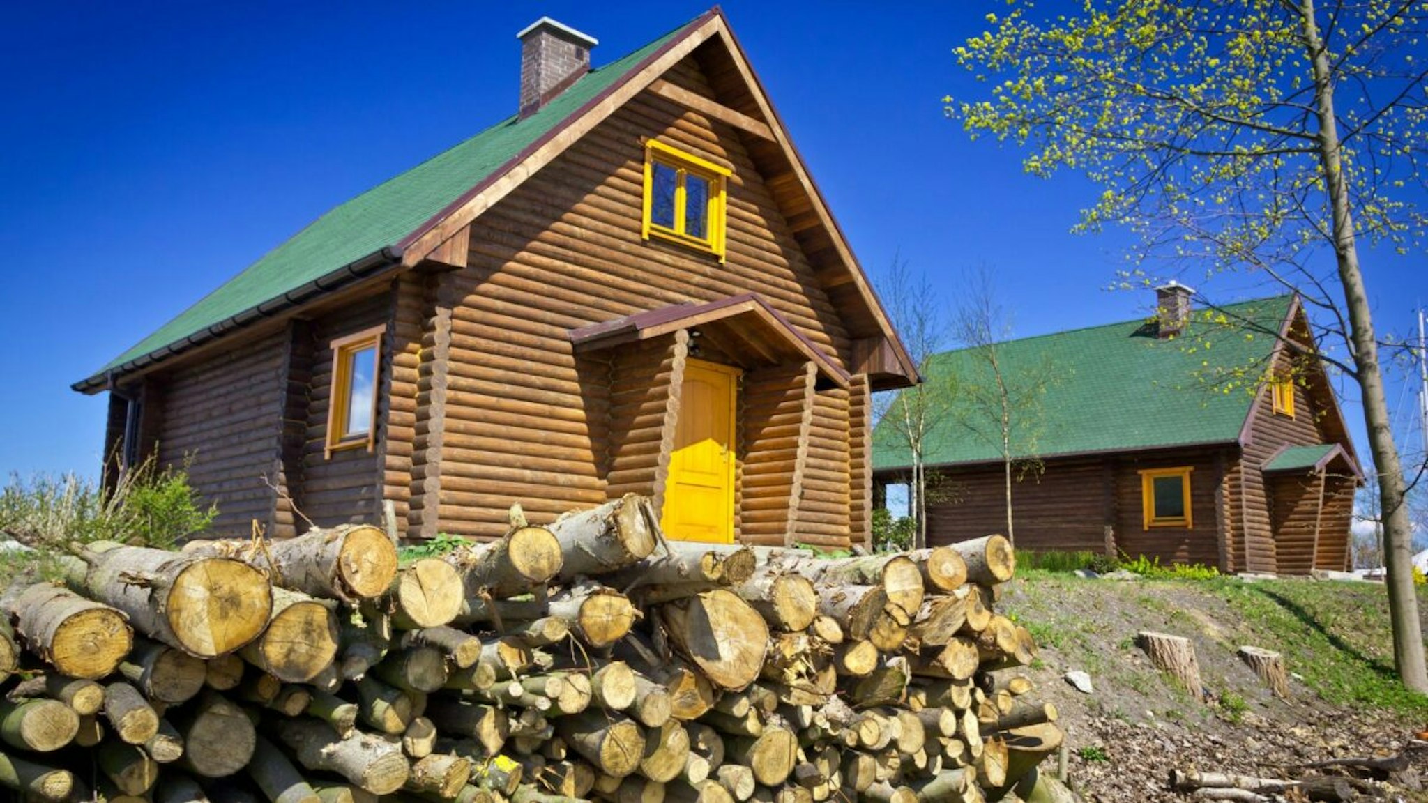 Spring view of the stacked Logs and camping cabins against blue sky
