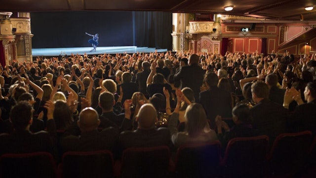 Audience applauding ballerina on stage in theater