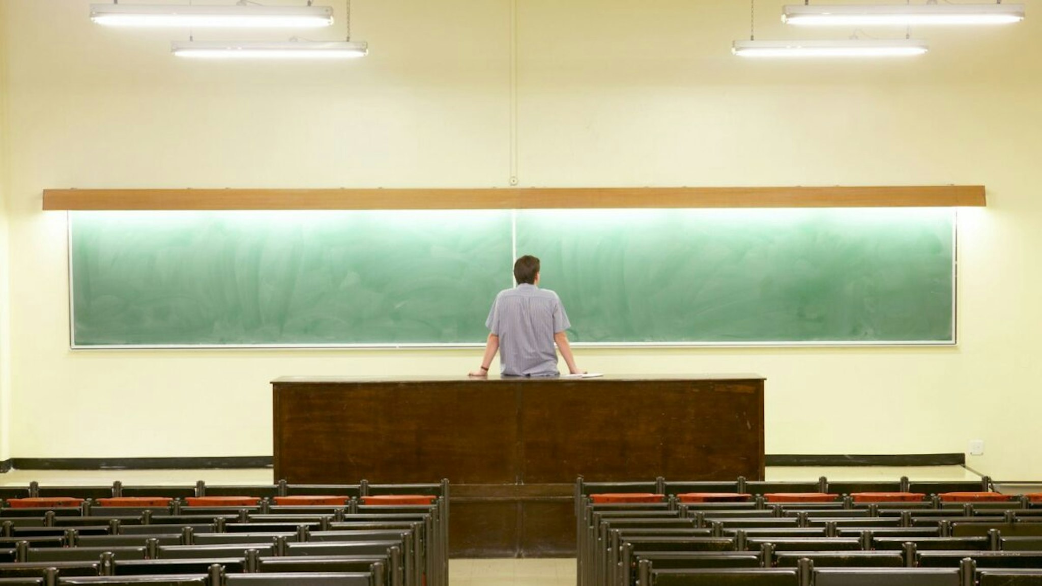 Man Staring at Blackboard in Empty Lecture Hall