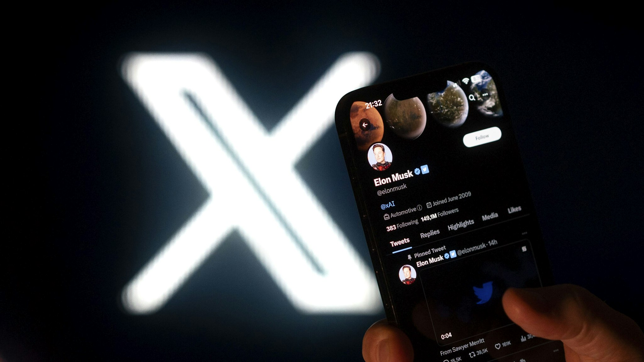 Elon Musk's Twitter page is seen on a mobile device with the X logo in the background in this photo illustration on 23 July, 2023 in Warsaw, Poland.