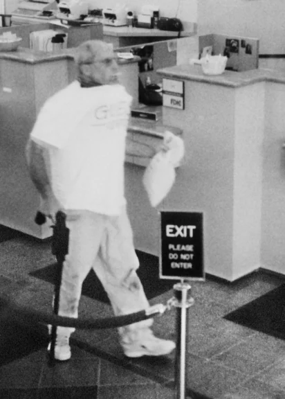 In this photo released Sept. 17, 2005, by the FBI, Brian Wells, 46, of Erie, Pa., carries a plastic bag of cash after robbing the PNC Bank in Summit Towne Centre in Erie on Aug. 28, 2003. Wells is shown sucking on a lollipop inside the bank, wearing a collar bomb and carrying a cane-shaped firearm.AP
