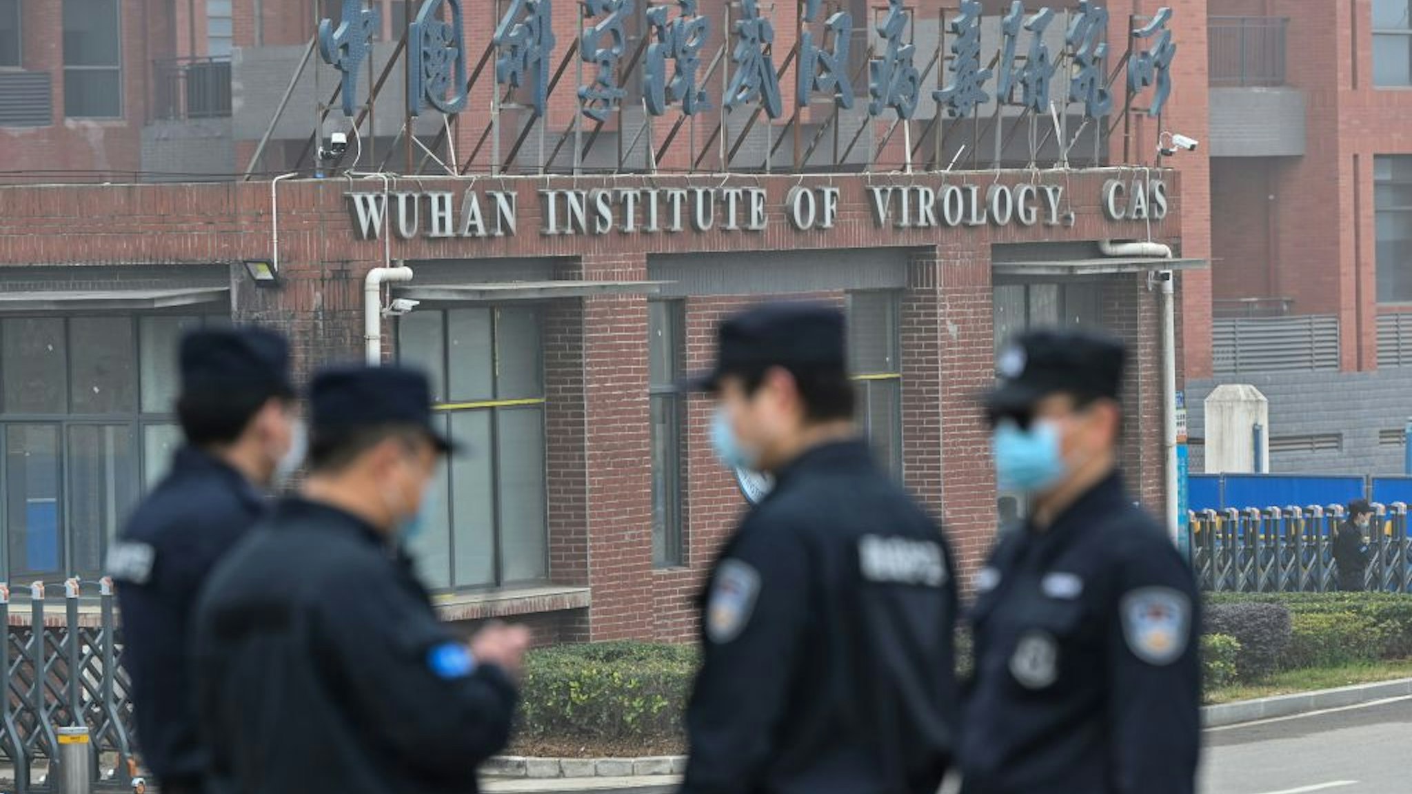 Security personnel stand guard outside the Wuhan Institute of Virology in Wuhan as members of the World Health Organization (WHO) team investigating the origins of the COVID-19 coronavirus make a visit to the institute in Wuhan in China's central Hubei province on February 3, 2021. (Photo by Hector RETAMAL / AFP)