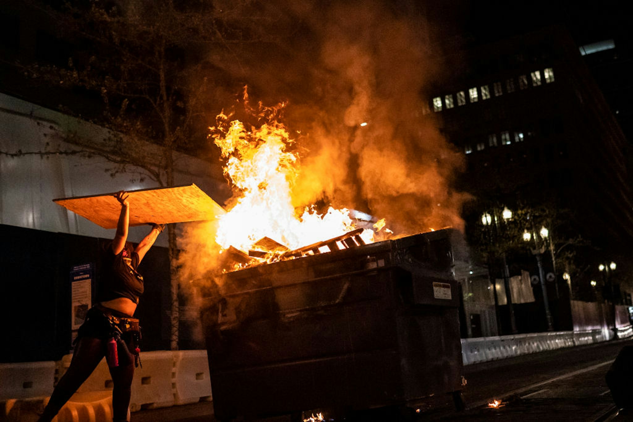 PORTLAND, OR - APRIL 16: A protester adds wood to a dumpster fire on April 16, 2021 in Portland, Oregon. Protests erupted Friday after Portland Police shot and killed a homeless man in Lents Park.