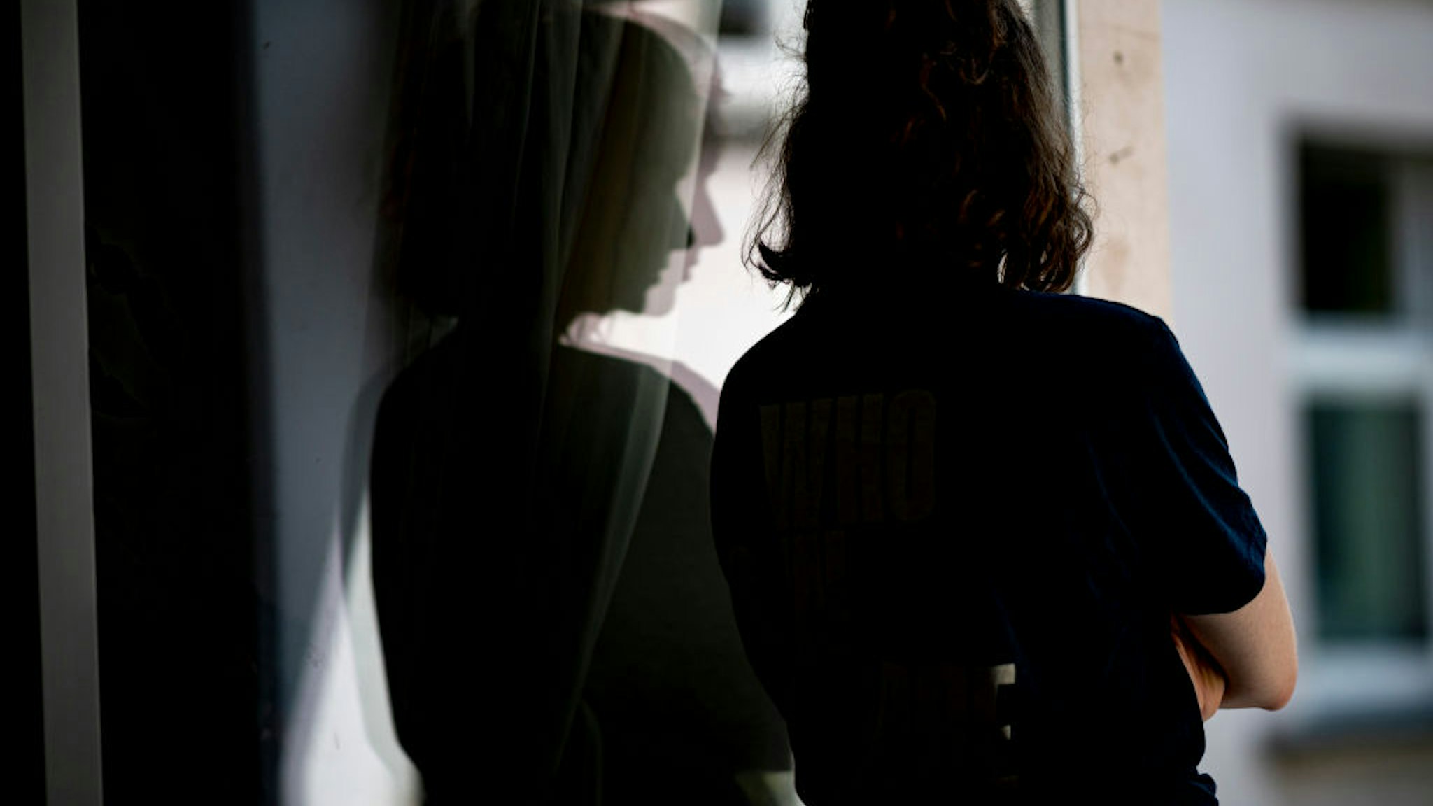 PRODUCTION - 13 July 2021, Berlin: ILLUSTRATION - A woman stands at a window in her apartment with her arms crossed. (posed scene) Photo: Fabian Sommer/dpa (Photo by Fabian Sommer/picture alliance via Getty Images)