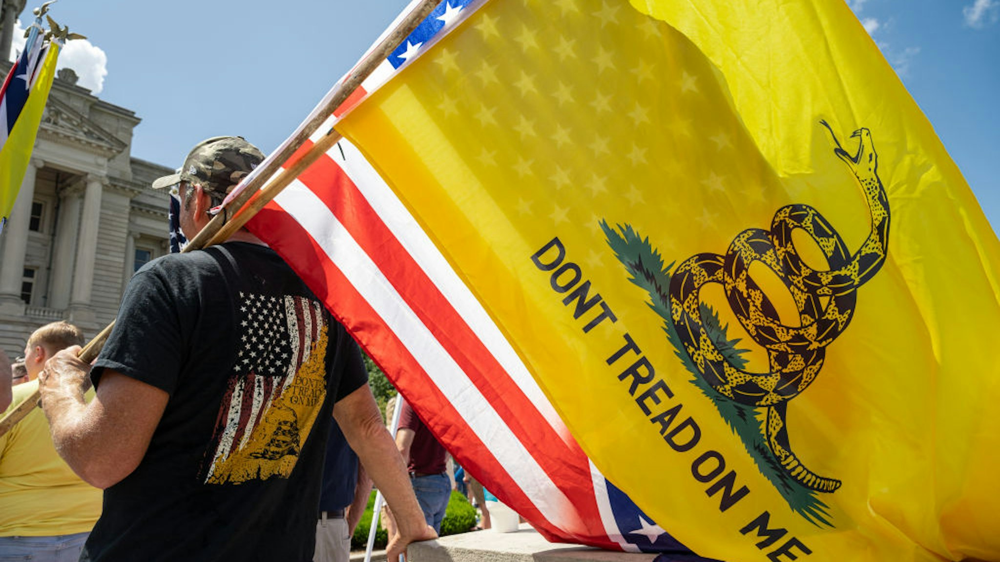 FRANKFORT, KY - AUGUST 28: A man with a Gadsden flag, a US flag, and a Confederate battle flag listens to a speaker during the Kentucky Freedom Rally at the capitol building on August 28, 2021 in Frankfort, Kentucky. Demonstrators gathered on the grounds of the capitol to speak out against a litany of issues, including Kentucky Gov. Andy Beshears management of the coronavirus pandemic, abortion laws, and the teaching of critical race theory. Demonstrators and speakers also refuted the legitimacy of the 2020 United State presidential election, claiming that former President Donald Trump won and should be reinstated. (Photo by Jon Cherry/Getty Images)