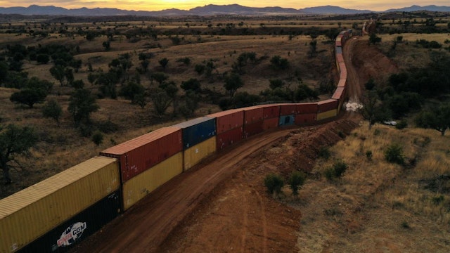 TOPSHOT - An aerial image shows a border wall constructed of shipping containers and topped with concertina wire built on federal land by Republican governor Doug Ducey, along the US-Mexico border in the Coronado National Forest near Hereford, Arizona on December 20, 2022. - Arizona agreed Wednesday to dismantle a wall of shipping containers at the Mexican border that critics said was an expensive, ecologically damaging political stunt that did nothing to keep migrants out. The state's Republican Governor Doug Ducey spent $90 million of taxpayers' money lining up rusting boxes in what he said was a bid to stem the flow of people crossing into the United States. (Photo by Patrick T. Fallon / AFP)