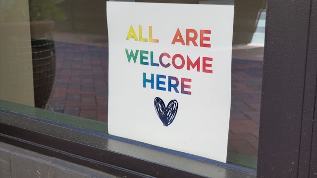 A sign with a message of inclusion and a rainbow color motif is visible in the window of a storefront in Orinda, California, August 21, 2020. (Photo by Smith Collection/Gado/Getty Images)