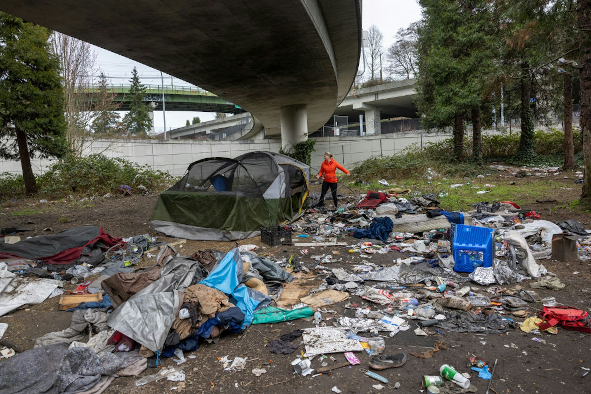 SEATTLE, WASHINGTON - MARCH 13: Andrea Suarez dismantles a tent as garbage lies piled at a homeless encampment on March 13, 2022 in Seattle, Washington. The accumulation of garbage at such sites has become a major issue in Seattle as the city tries to move the unhoused out of shared public spaces. Suarez is the executive director of We Heart Seattle, a non-profit that stages trash cleanups across the city. According to a recent report commissioned by Seattle Councilmember Andrew Lewis, the COVID-19 pandemic put undue pressure on the city's shelter system and delayed funds for new housing, leading to an increase in homelessness. (Photo by John Moore/Getty Images)