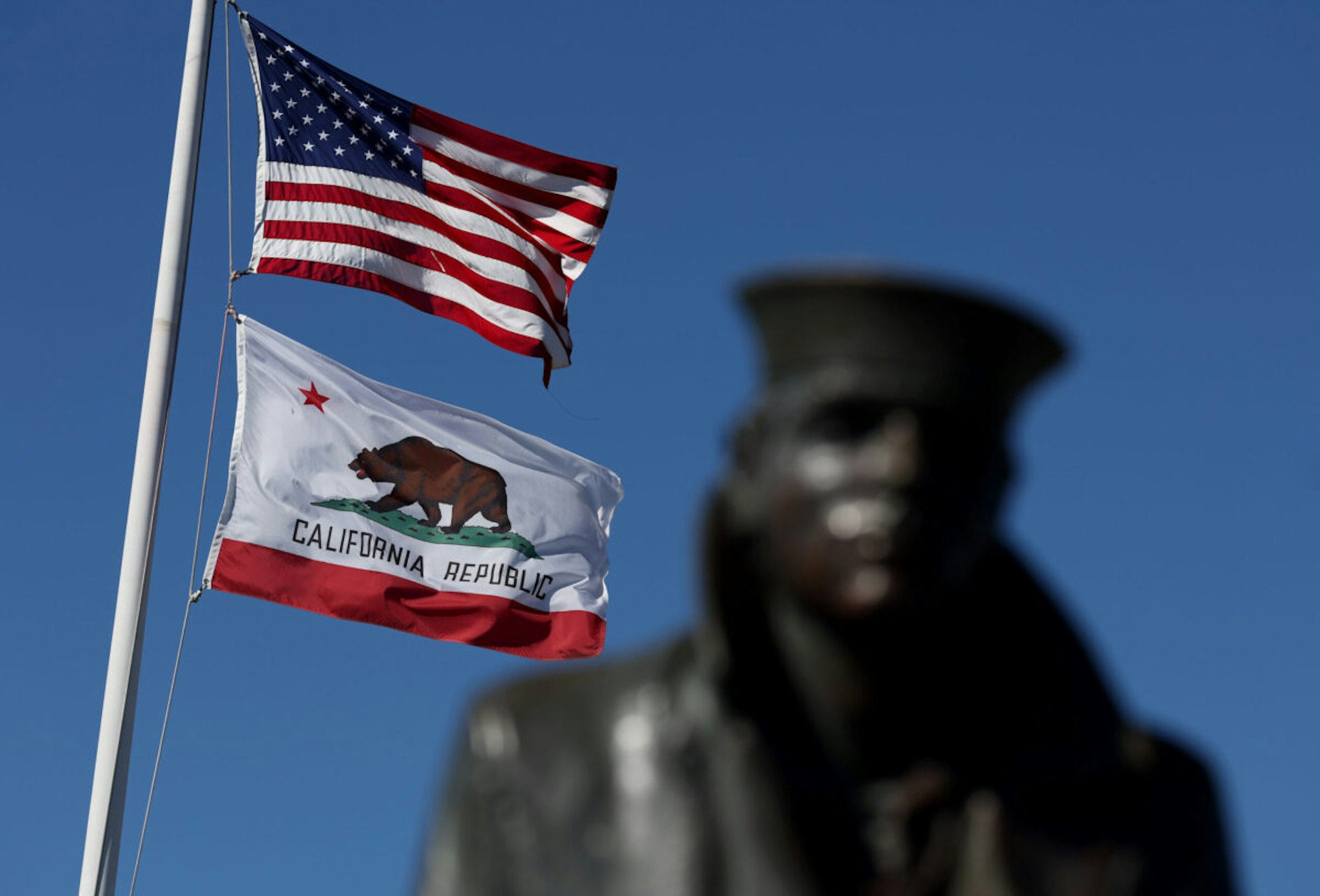 An American flag flies with the California State flag next to the Lone Sailor statue on October 24, 2022 in Sausalito, California.