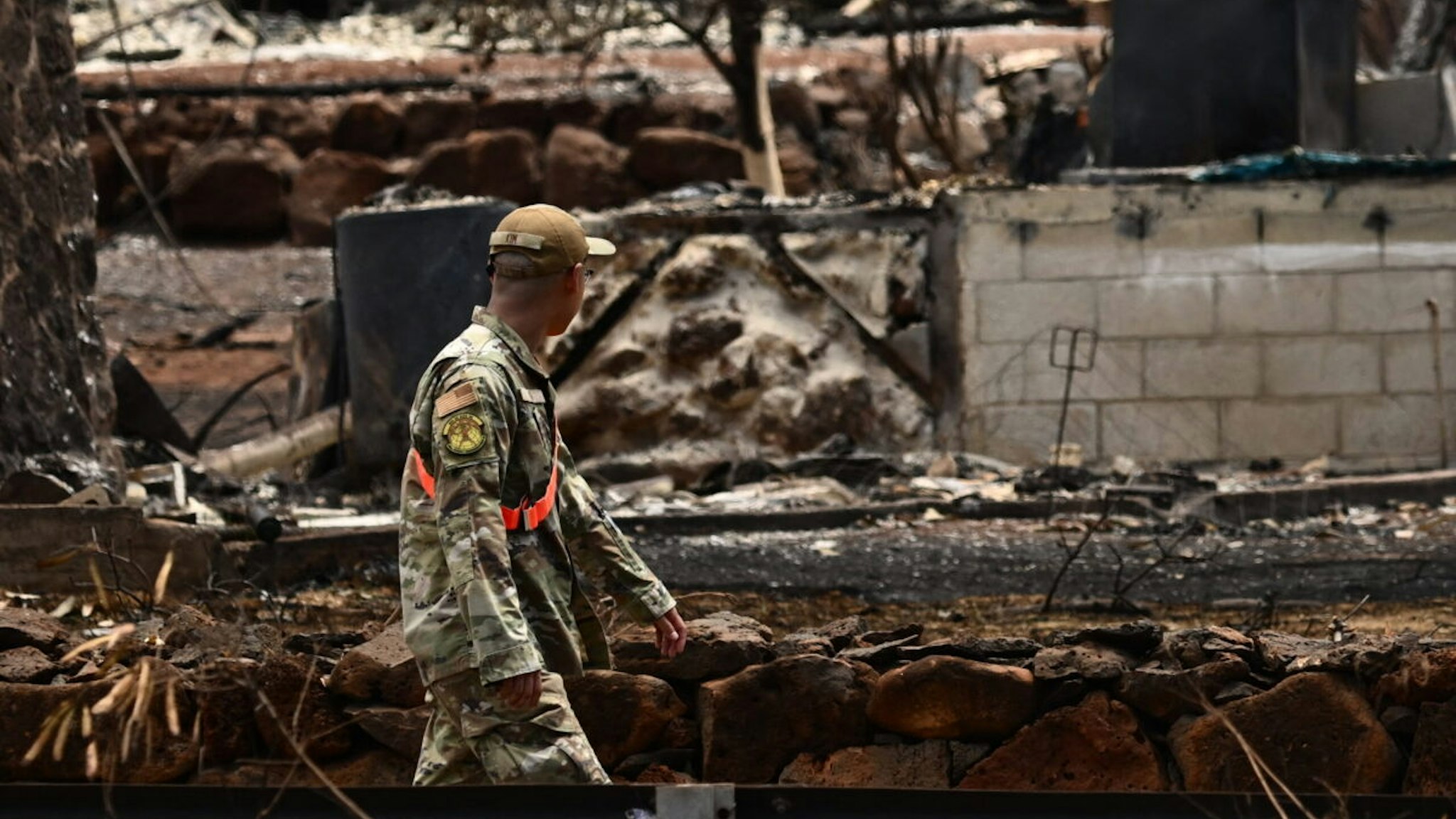 A member of the National Guard walks through a charred neighborhood in the aftermath of the Maui wildfires in Lahaina, Hawaii, on August 16, 2023. The number of people known to have died in the horrific wildfire that levelled a Hawaiian town reached 106 on August 15, authorities said, as a makeshift morgue was expanded to deal with the tragedy. US President Joe Biden will head to fire-ravaged Hawaii on August 21 to meet with survivors and first responders still hunting for victims, the White House said on August 16.