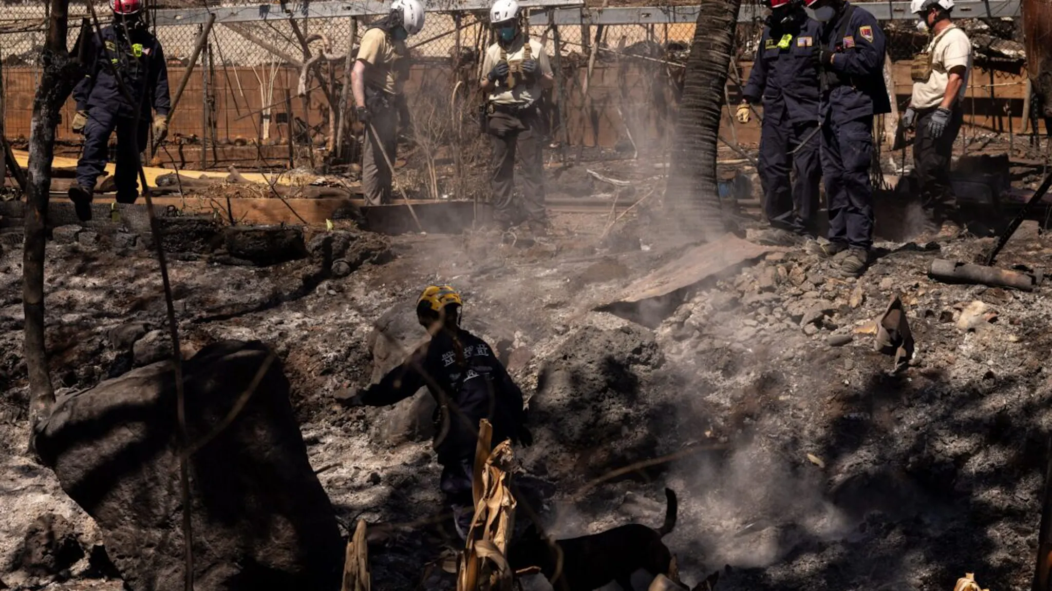 Maui Wildfire TOPSHOT - Search and recovery team members check charred buildings and cars in the aftermath of the Maui wildfires in Lahaina, Hawaii, on August 18, 2023. At least 111 people are known to have died in what was the deadliest wildfire in the US in over a century. The final toll is expected to be considerably higher.