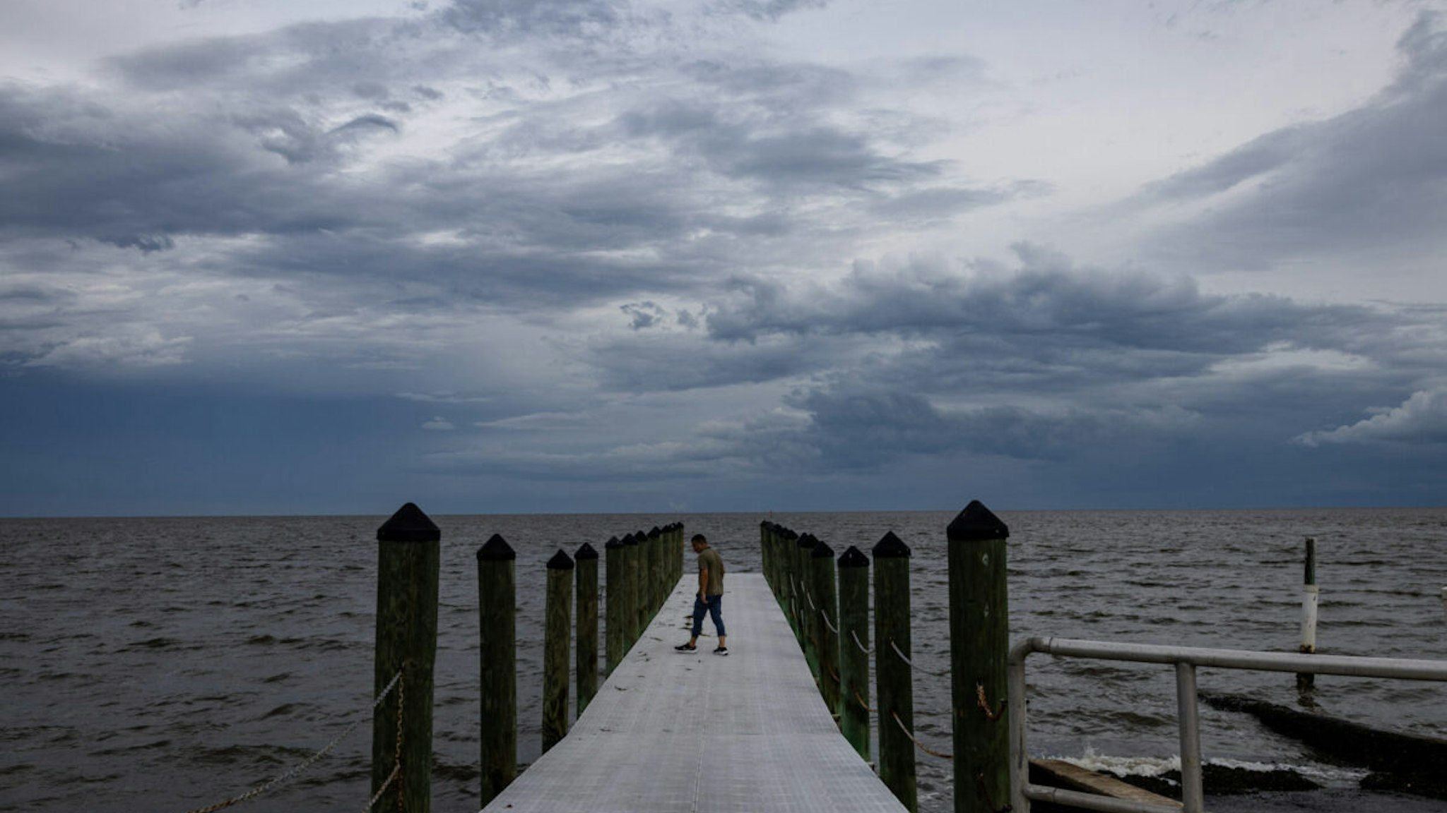 A news reporter walks onto a dock ahead of Hurricane Idalia in Cedar Key, Florida, US, on Tuesday, Aug. 29, 2023.